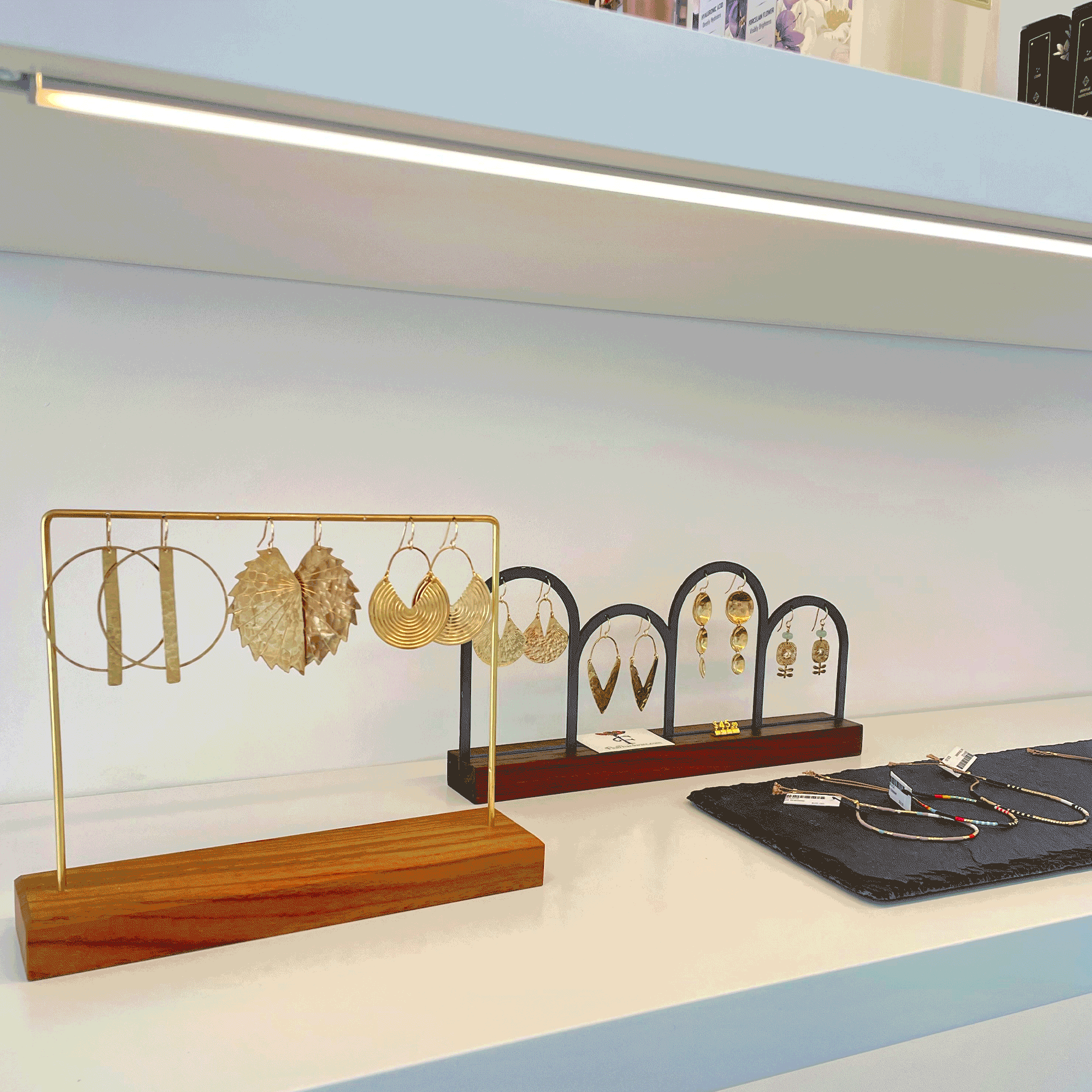“Looping animation of a curated jewelry display at International Orange, featuring elegant gold earrings on minimal stands and handcrafted pieces laid on slate trays, set against clean white shelving in a modern boutique setting.